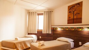 A hotel room with two beds, a window with curtains, a wooden headboard, and a painting of a tree. - Pousada Bahia Brasil (Cairu)