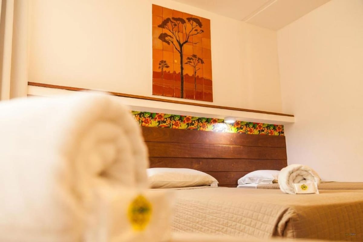 Une chambre d’hôtel avec un lit, des oreillers, une tête de lit et un tableau au mur.