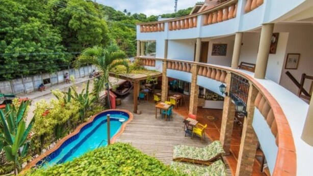 A multi-level building with a pool, outdoor seating, and lush greenery. - Pousada Bahia Brasil (Cairu)