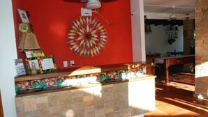 A reception area with a red wall, a decorative fish wall art, and a tiled floor. - Pousada Bahia Brasil (Cairu)
