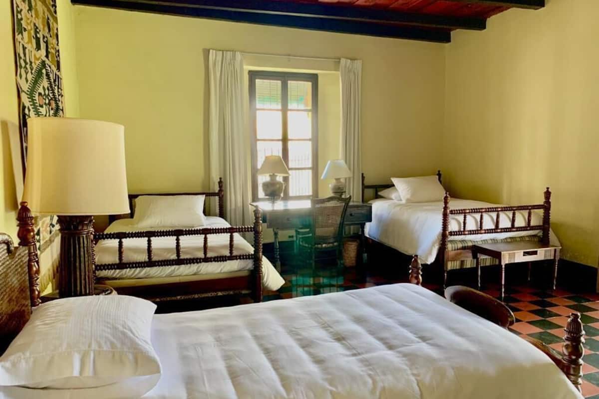 A room with two wooden beds, a table, and a chair.