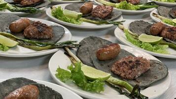 A table with multiple plates of food, each containing meat, lettuce, and lime slices.