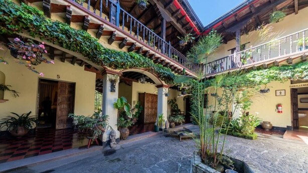 A courtyard with a checkered floor, wooden doors, and potted plants. - Hotel Museo Mayan Inn de Guatemala (Chichicastenango)