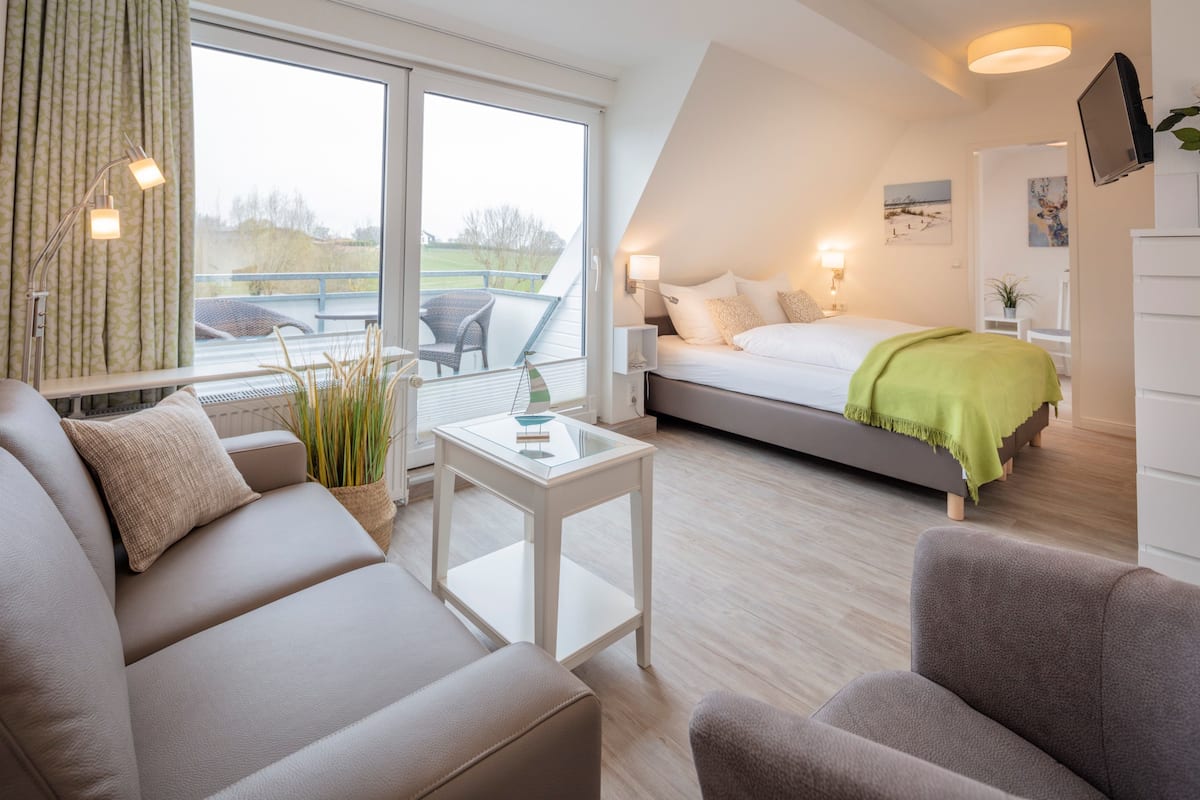 A modern bedroom with a bed, a sofa, a small table, and a TV.