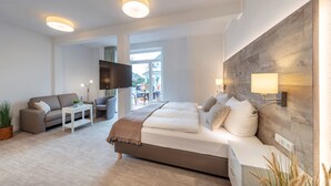 Una habitación de hotel moderna con una cama grande, un sofá, un televisor y vistas al exterior.