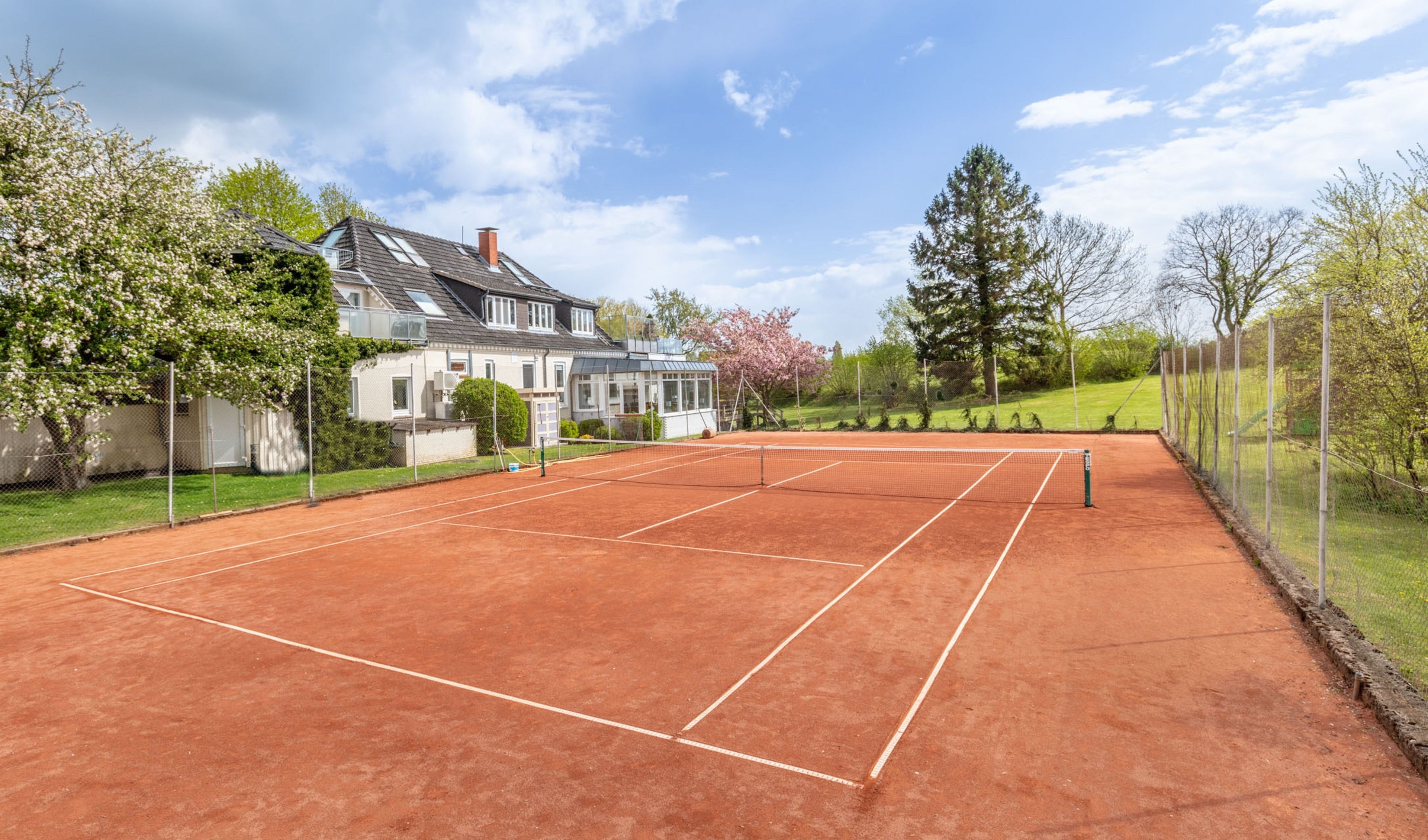 Un court de tennis avec une maison en arrière-plan.