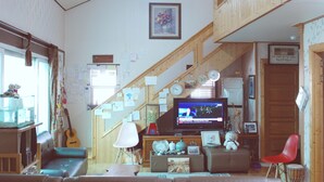 Una sala de estar acogedora con una escalera, un televisor y diversas decoraciones.