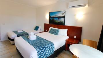 Habitación de hotel con dos camas, un cuadro grande de un puente, aire acondicionado y una mesita.