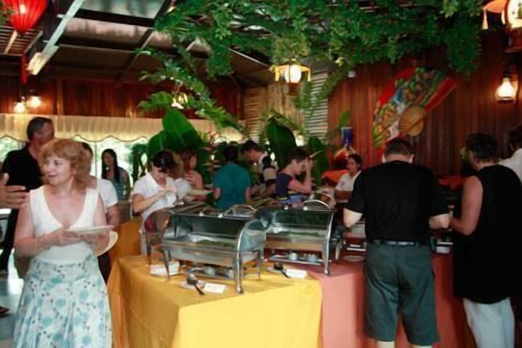 A buffet setup with multiple serving stations, surrounded by greenery and wooden decor.