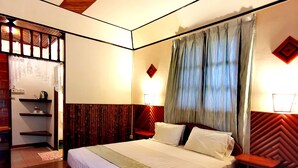 Une chambre bien éclairée, avec un grand lit, une tête de lit en bois et une table de chevet.