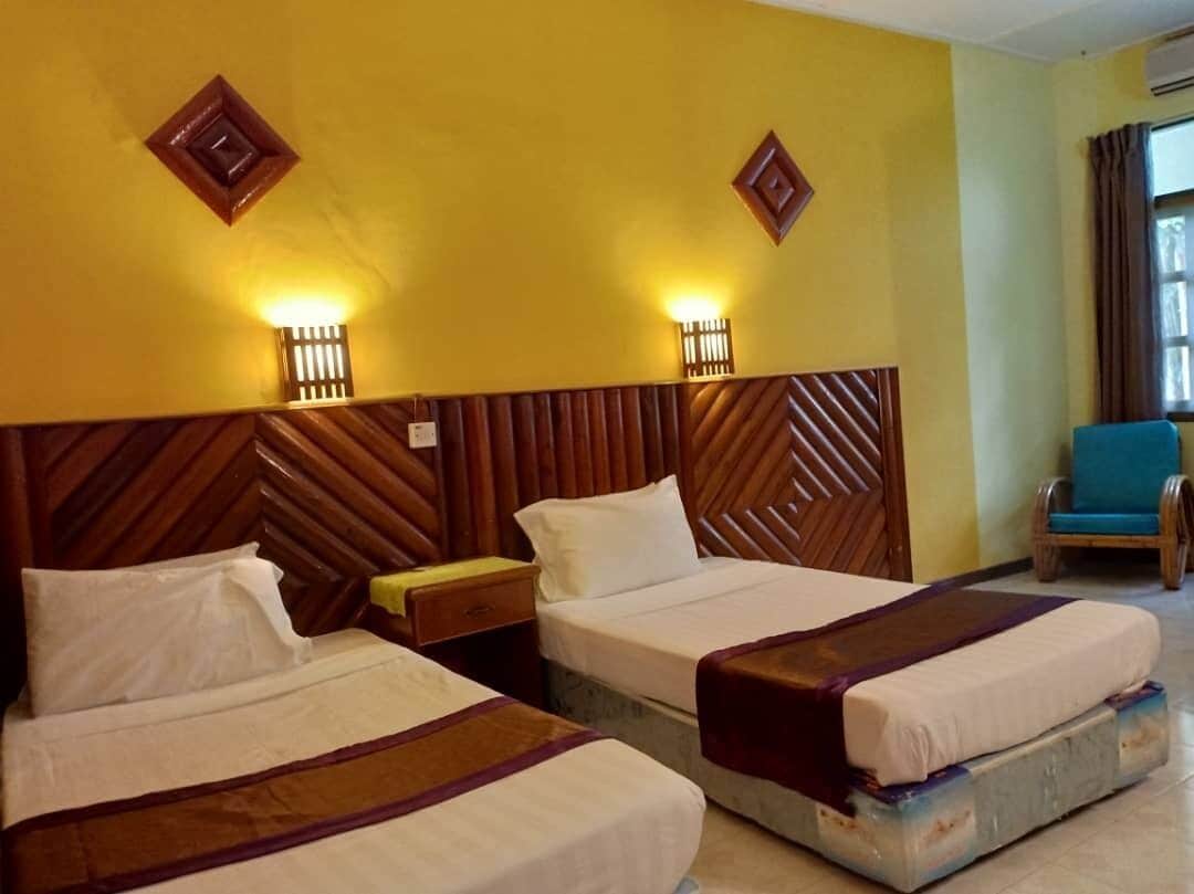 Une chambre d’hôtel avec deux lits, des têtes de lit en bois et des lampes fixées au mur.