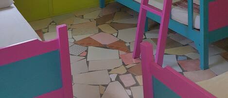 A room with bunk beds, a window with curtains, and a tiled floor.