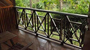 Une terrasse en bois dotée d’une rambarde métallique aux motifs géométriques, qui offre une vue sur un jardin luxuriant et verdoyant.