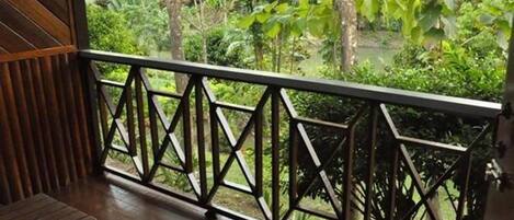 A wooden deck with a geometric metal railing, overlooking a lush green garden.