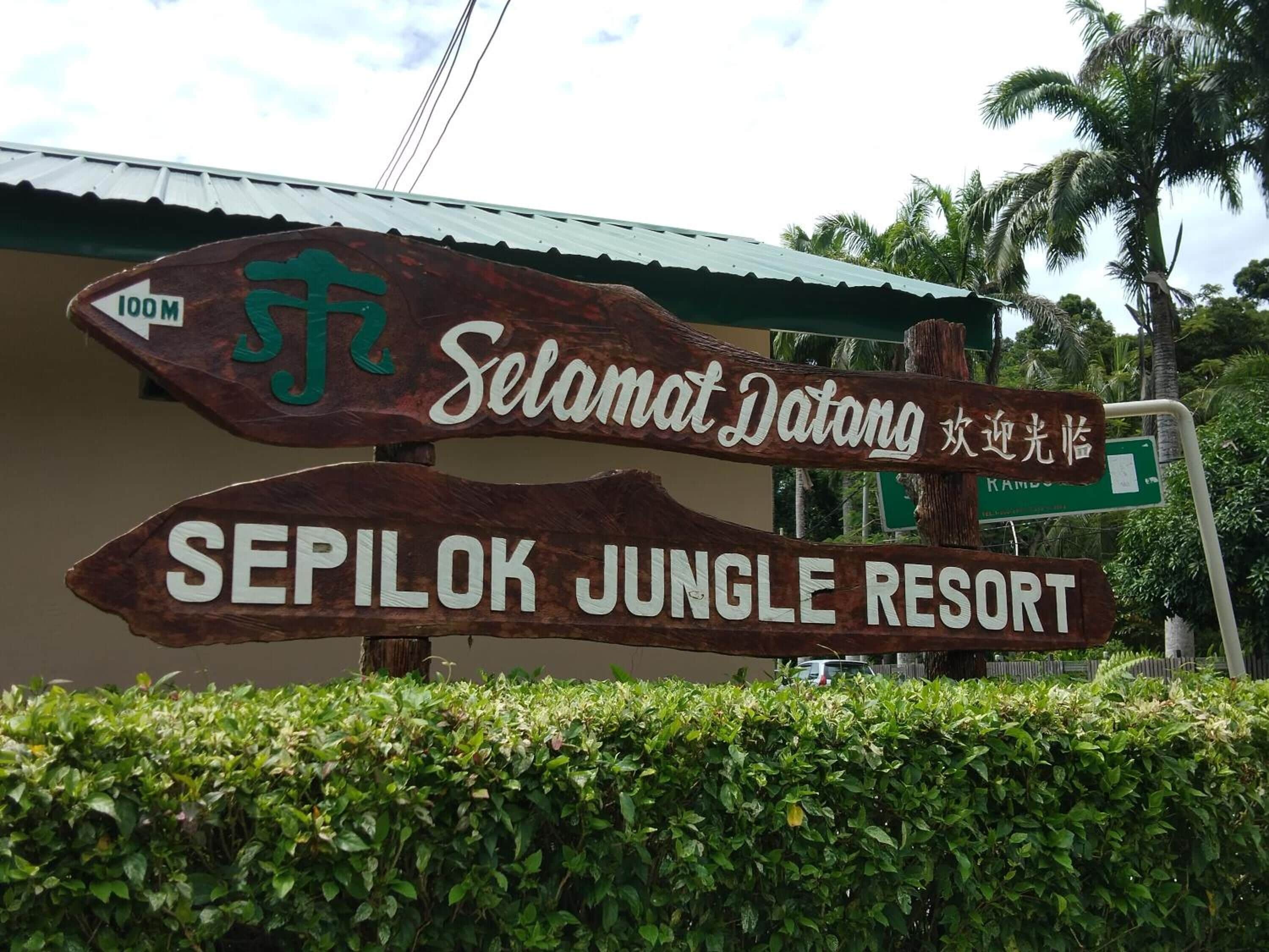 A wooden sign with 'Selamat Datang' and 'SEPILOK JUNGLE RESORT' written on it.