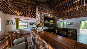 A rustic bar area with stone walls, wooden ceiling, and a bar counter. - Kunene River Lodge (Ruacana)