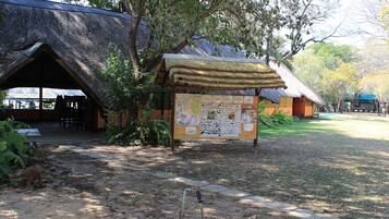 Un espacio rústico al aire libre con cabañas de techo de paja y un letrero de madera.