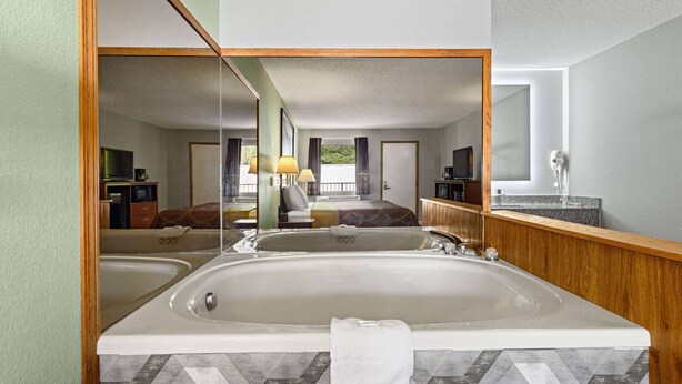 A bathroom with a large bathtub, a mirror, and a sink. - Super 8 by Wyndham Branson / Shepherd of the Hills Exwy (Branson)