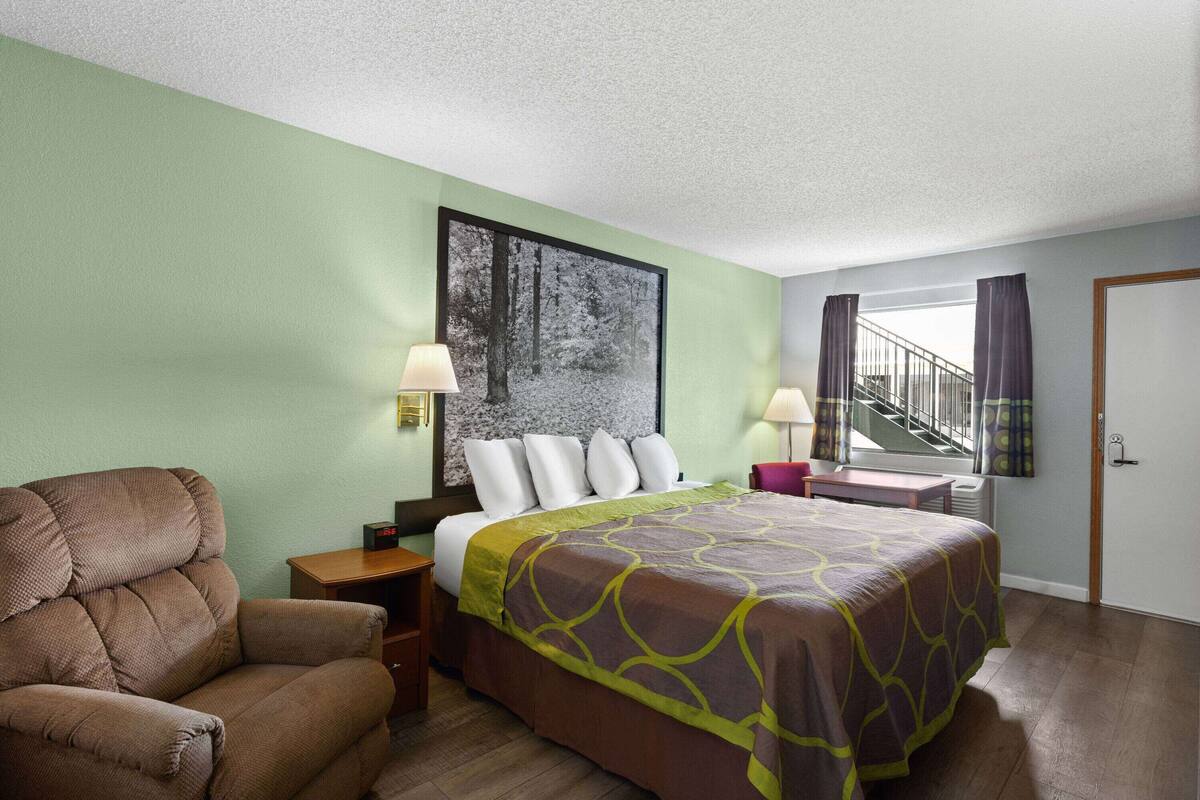 A hotel room with a bed, a chair, a desk, and a staircase.