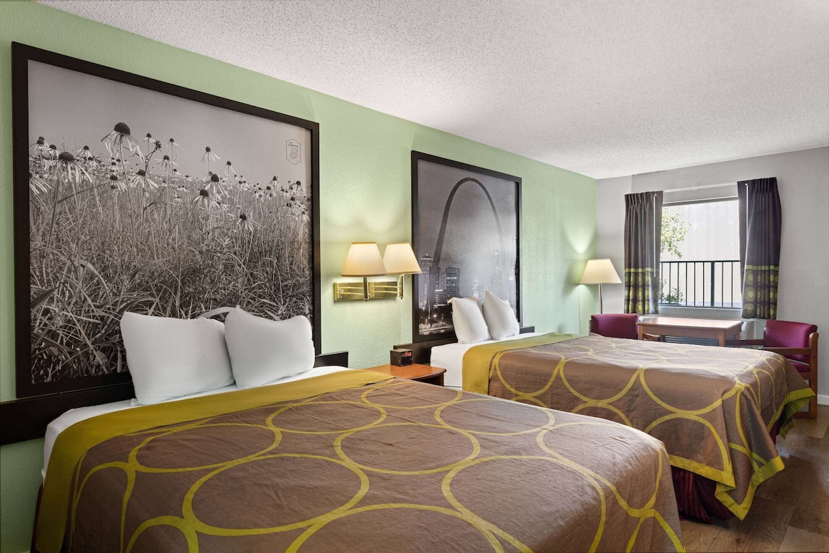 A hotel room with two beds, a desk, a chair, and a window with curtains.
