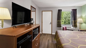 A hotel room with a wooden desk, television, and a bed with a patterned bedspread. - Super 8 by Wyndham Branson / Shepherd of the Hills Exwy (Branson)