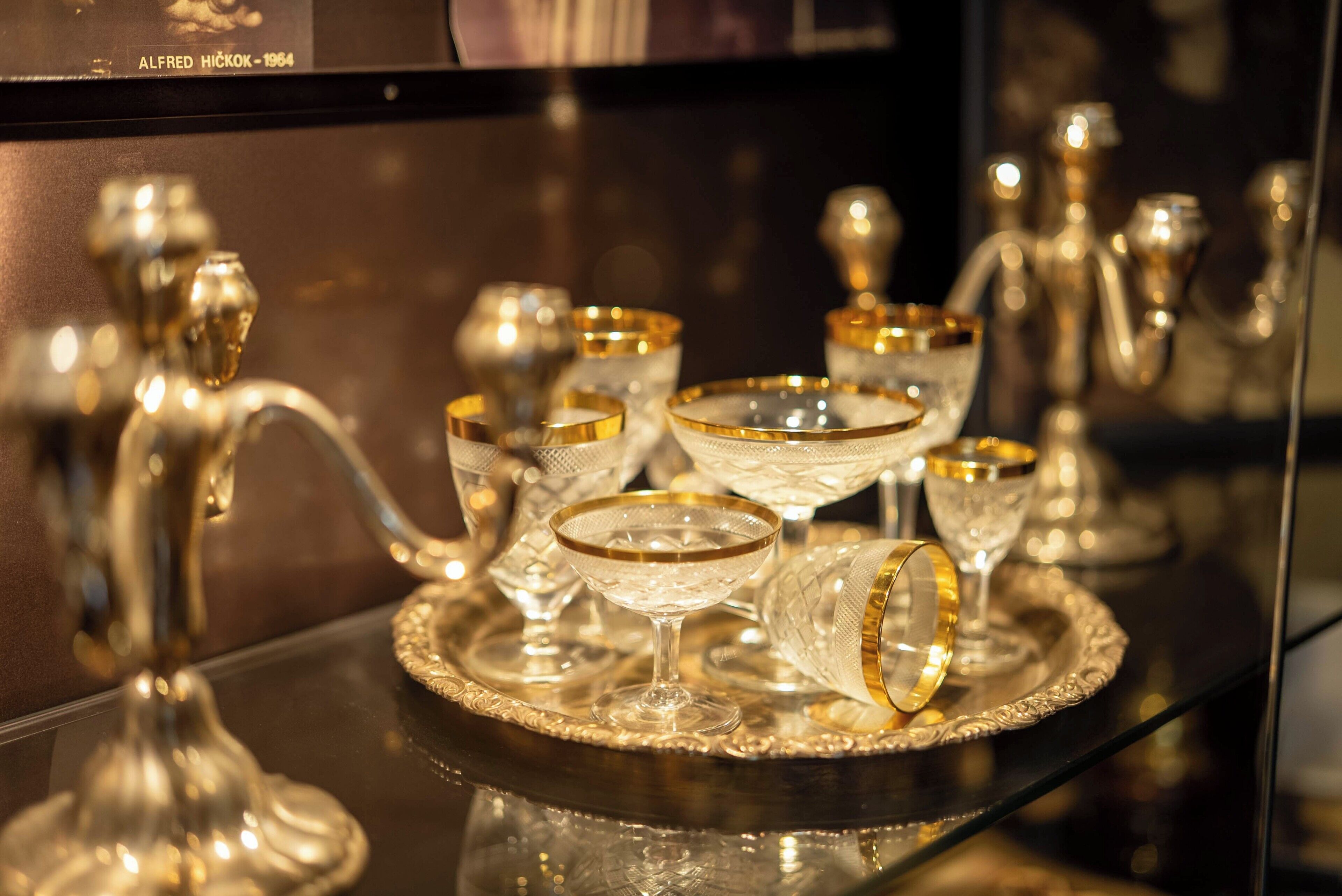 A display of crystal glassware with gold accents on a reflective surface.