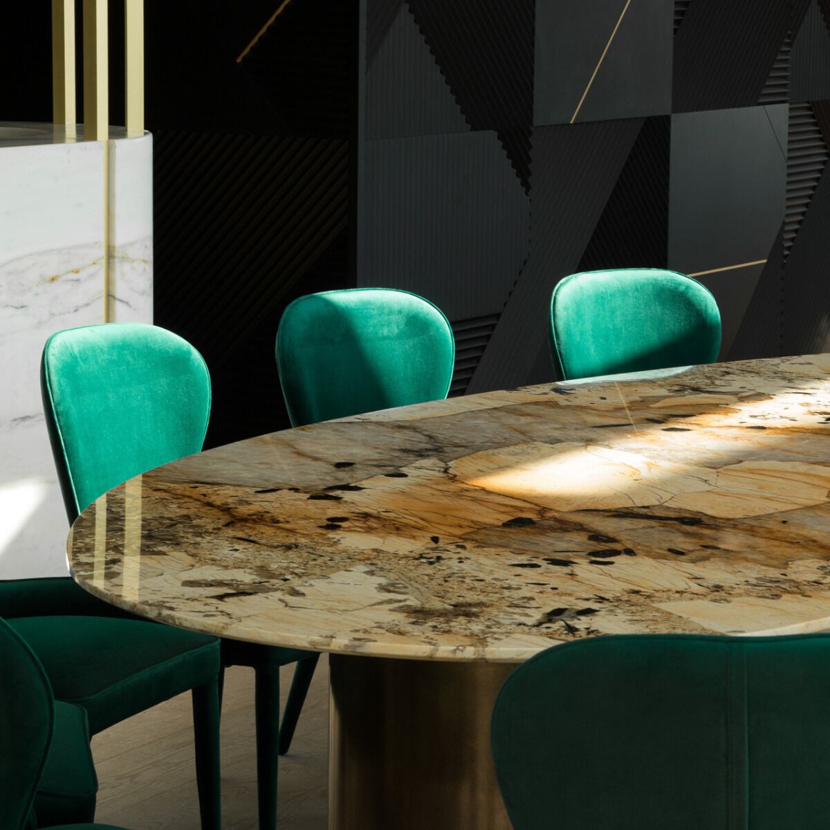 Una mesa redonda de mármol con una silla tapizada en verde.