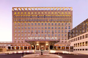 Un hotel grande y moderno con una entrada destacada y una fuente central.