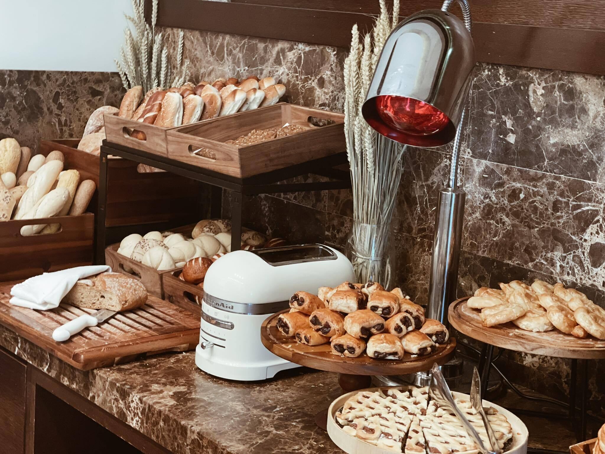 A bakery display with various breads and pastries, a toaster, and a decorative lamp.