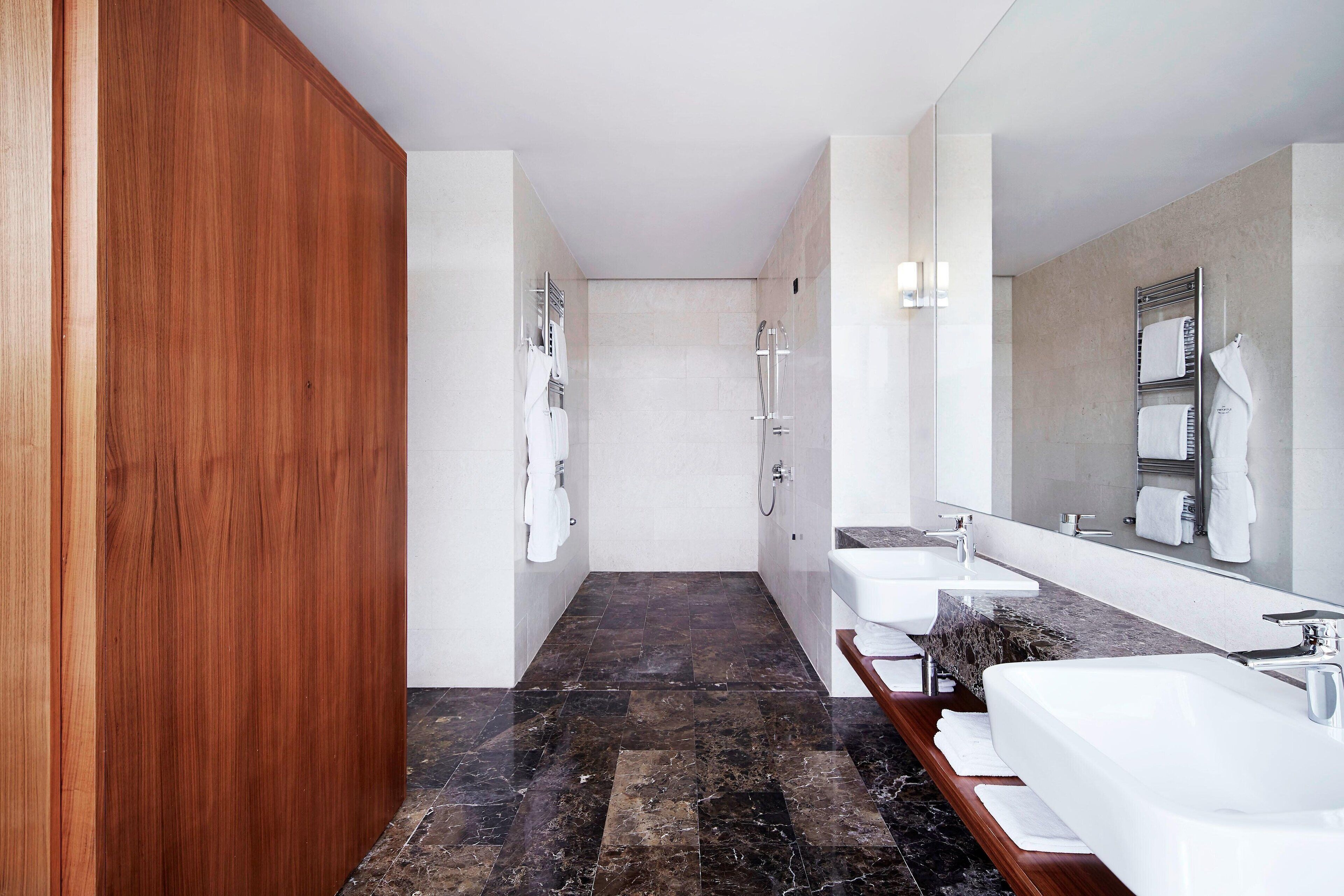Ein modernes Badezimmer mit Waschtisch aus Holz, einem großen Spiegel und einer Duschkabine.