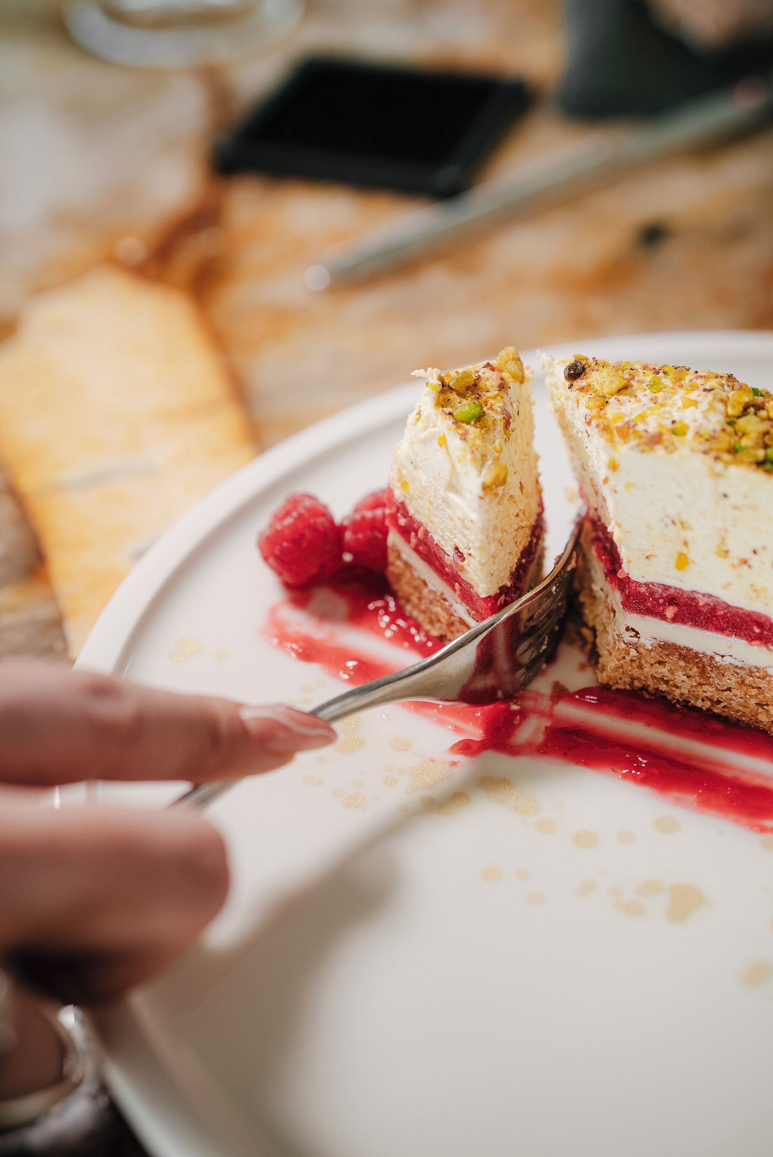 A slice of layered cake with cream and raspberries on a plate.