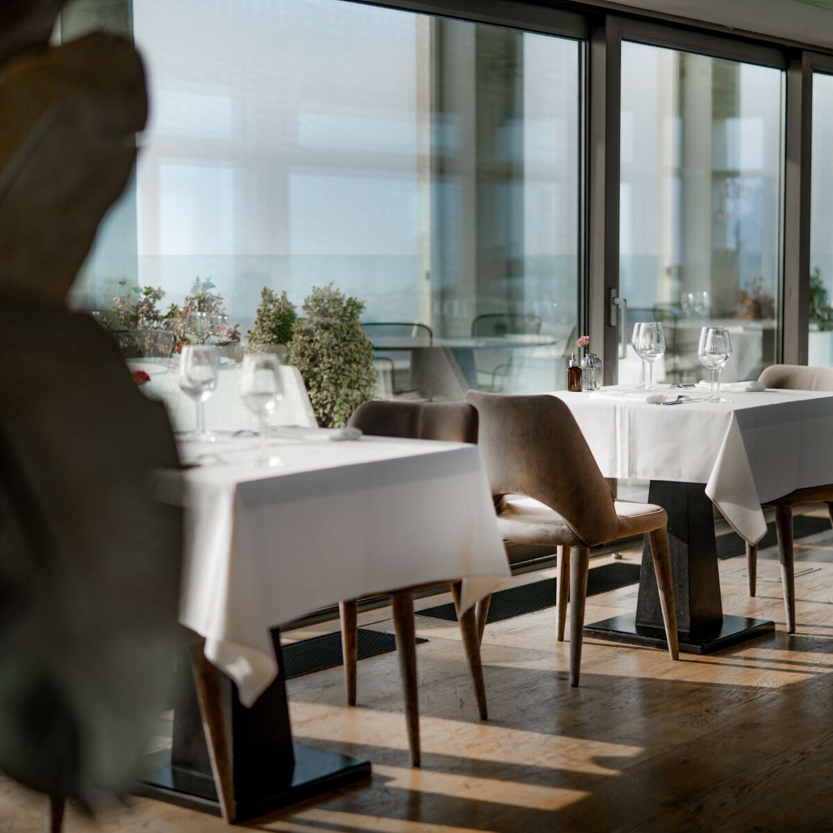 A restaurant with tables set for dining, large windows, and a view of the cityscape.