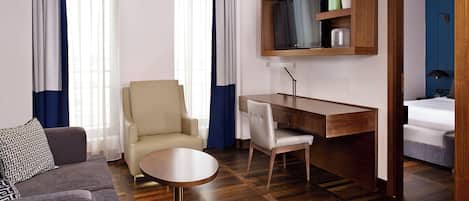 A hotel room with a sofa, a chair, a desk, and a bed.