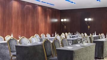 A conference room with rows of tables and chairs, equipped with water bottles and glasses.