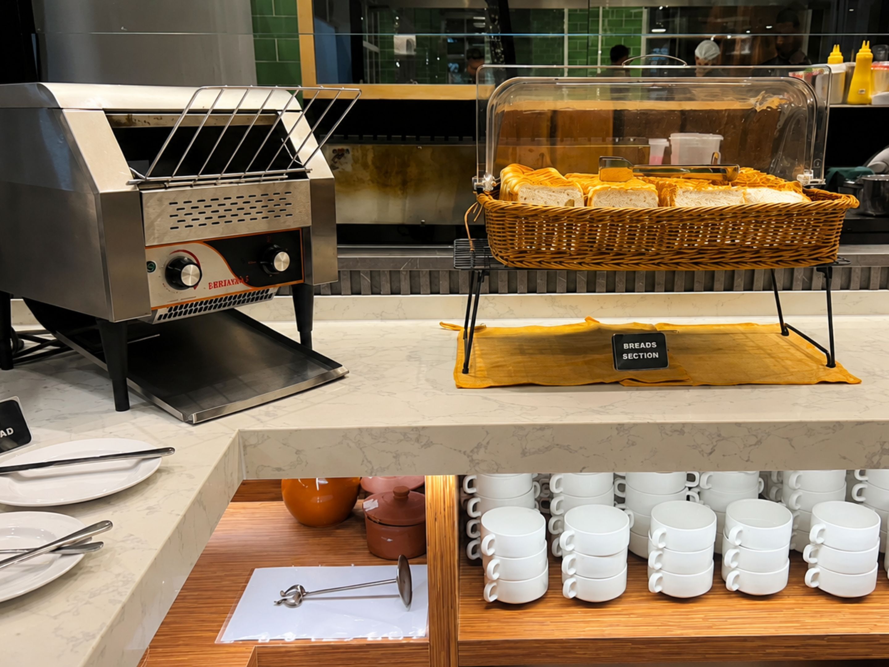 A bakery display with bread baskets and a coffee station with mugs.