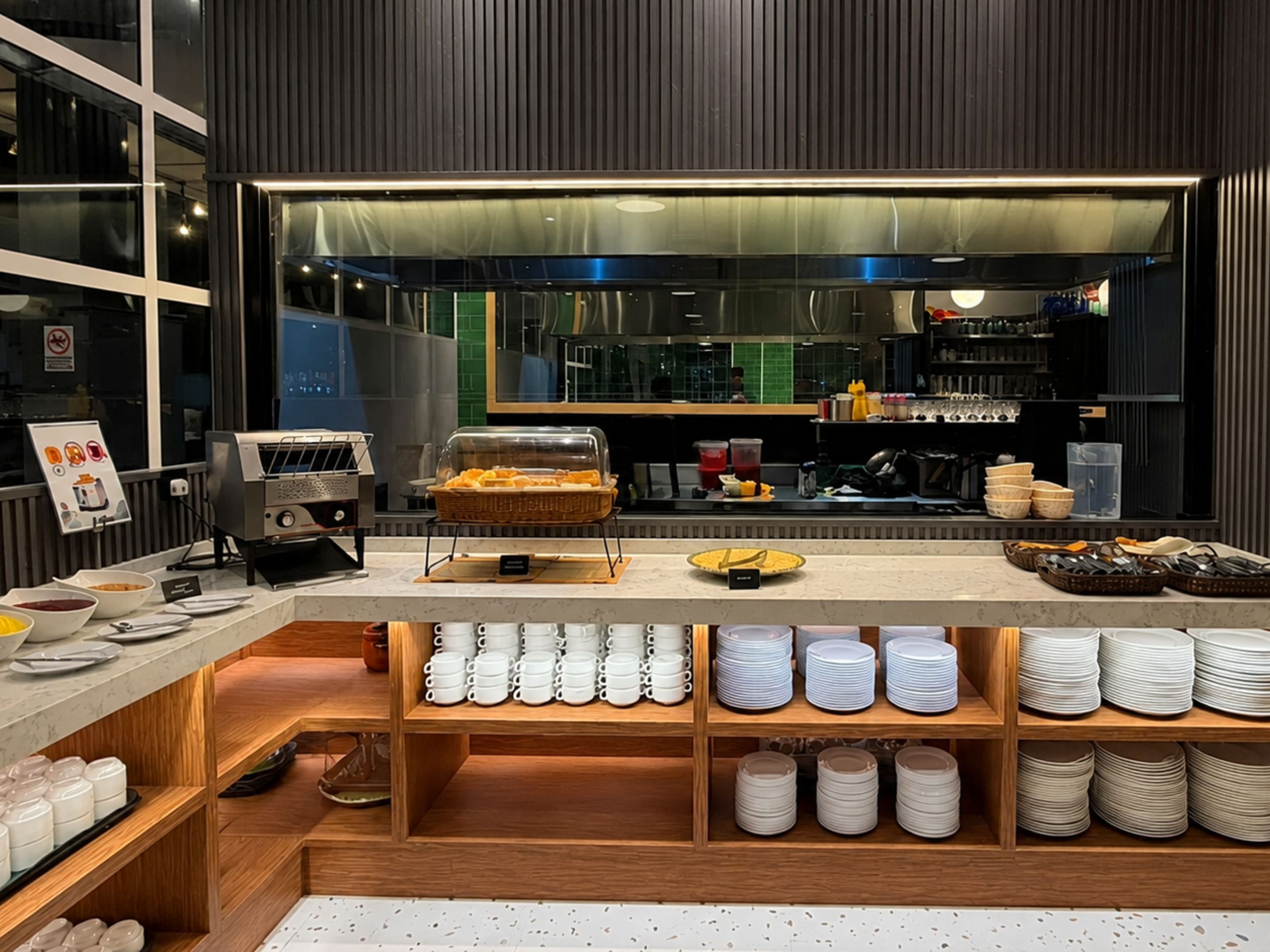 A buffet area with a variety of food items and a selection of white cups and plates.