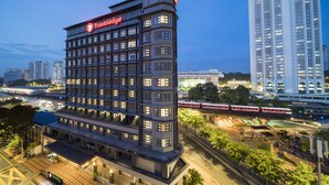 Een modern hotel met meerdere verdiepingen, een opvallend 'Travelodge' bord en uitzicht op een voorbijrijdende trein.