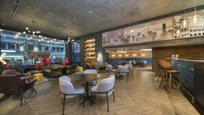 Een moderne lounge met zitplaatsen, een bar en een stadsgezicht muurschildering.