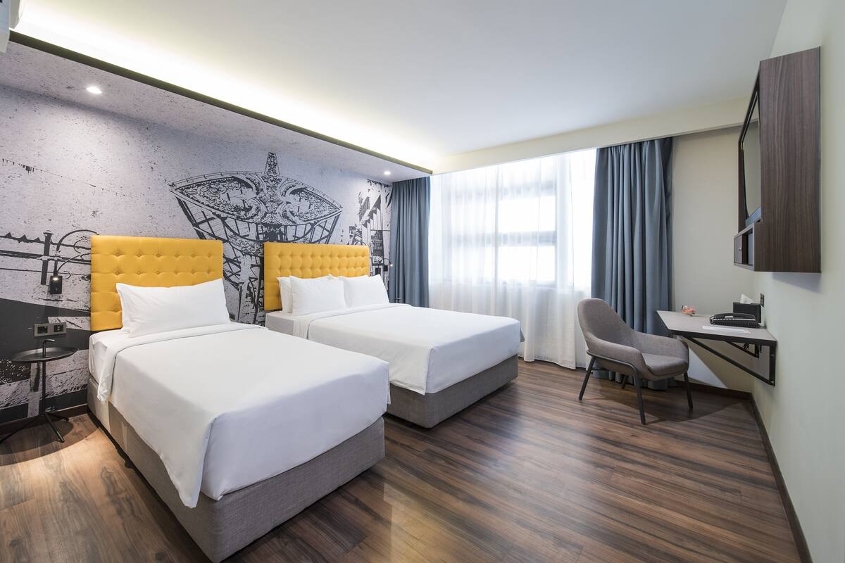 Une chambre d’hôtel avec deux lits, un bureau et une chaise.