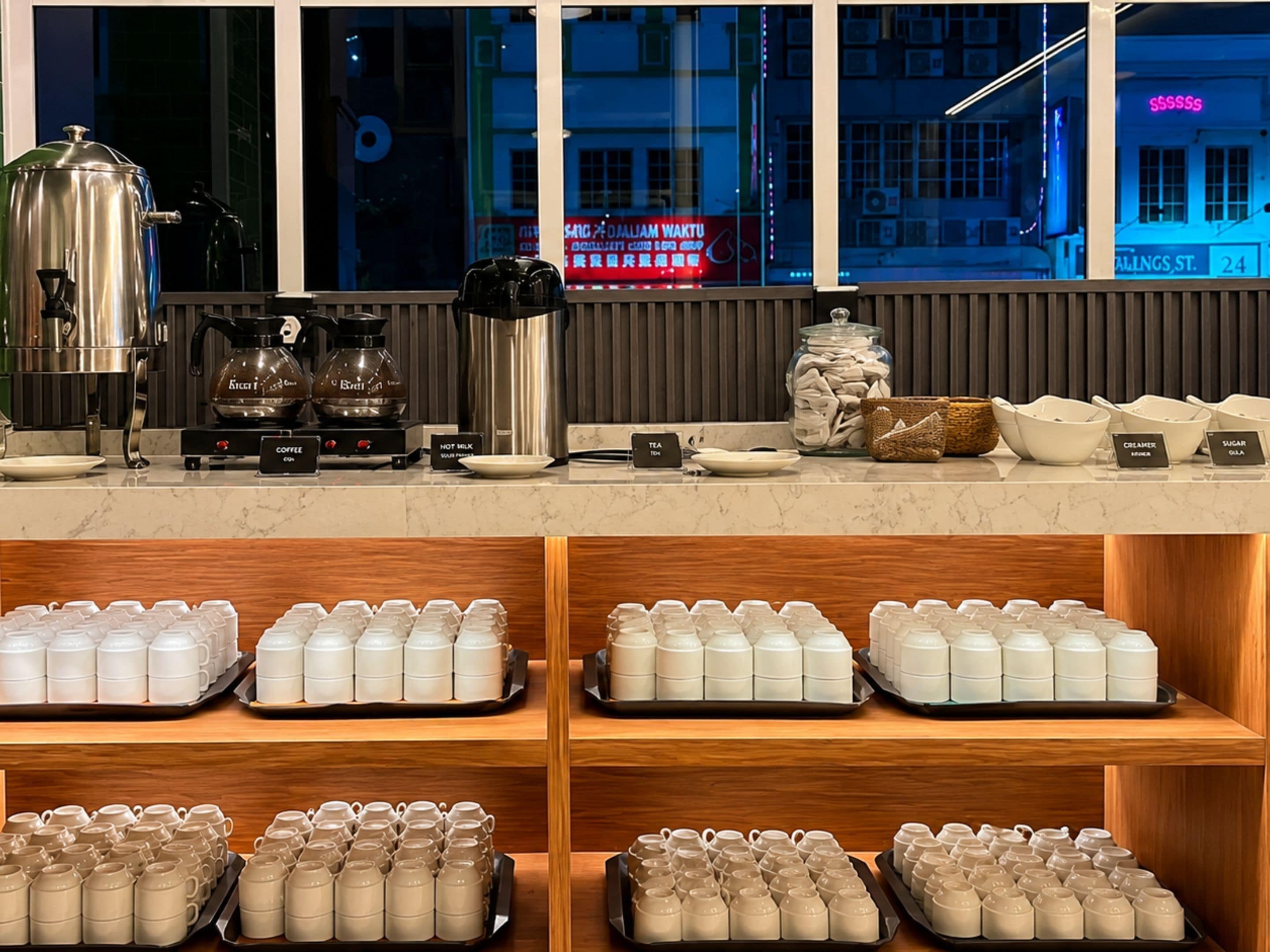 A coffee shop counter with brewing equipment, a tea station, and neatly arranged mugs on shelves.