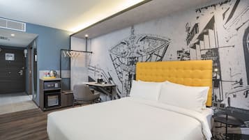 A hotel room with a large bed, a desk, a chair, and a wall mural.