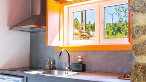 Una cocina moderna con ventana integrada, pileta de acero inoxidable y campana extractora.
