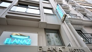 El exterior del Hotel Elanaz, con un llamativo letrero de neón y barandilla de balcón.