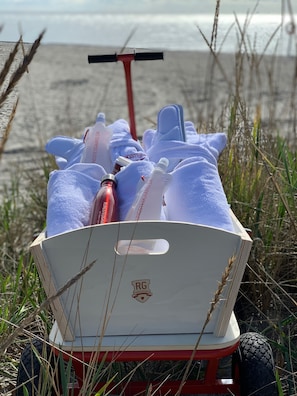 A cart with towels and toiletries on a beach.