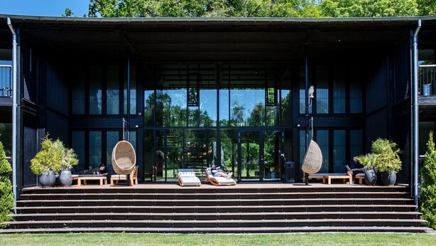 A modern building with a covered outdoor seating area, steps leading up to it, and potted plants. - Rungstedgaard (Rungsted Kyst)