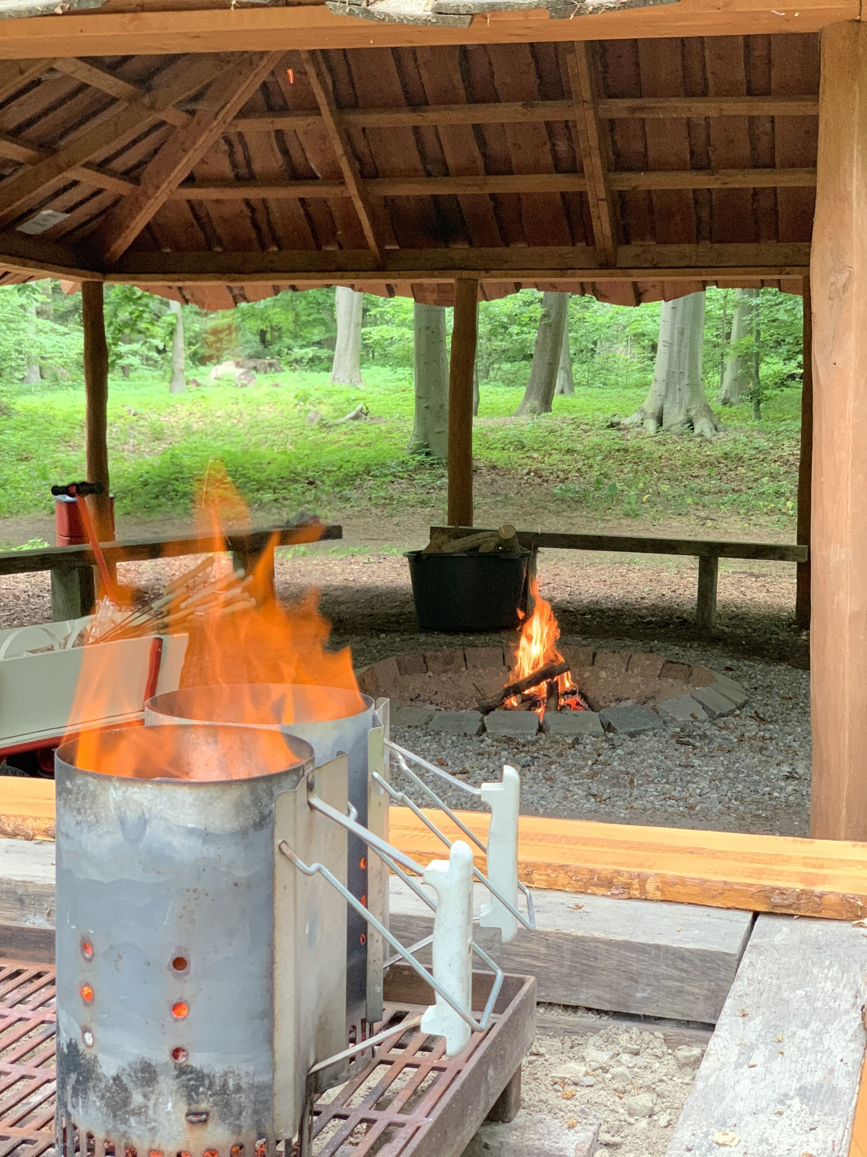 Un espacio al aire libre techado con una parrilla de metal y un pozo para fuego.