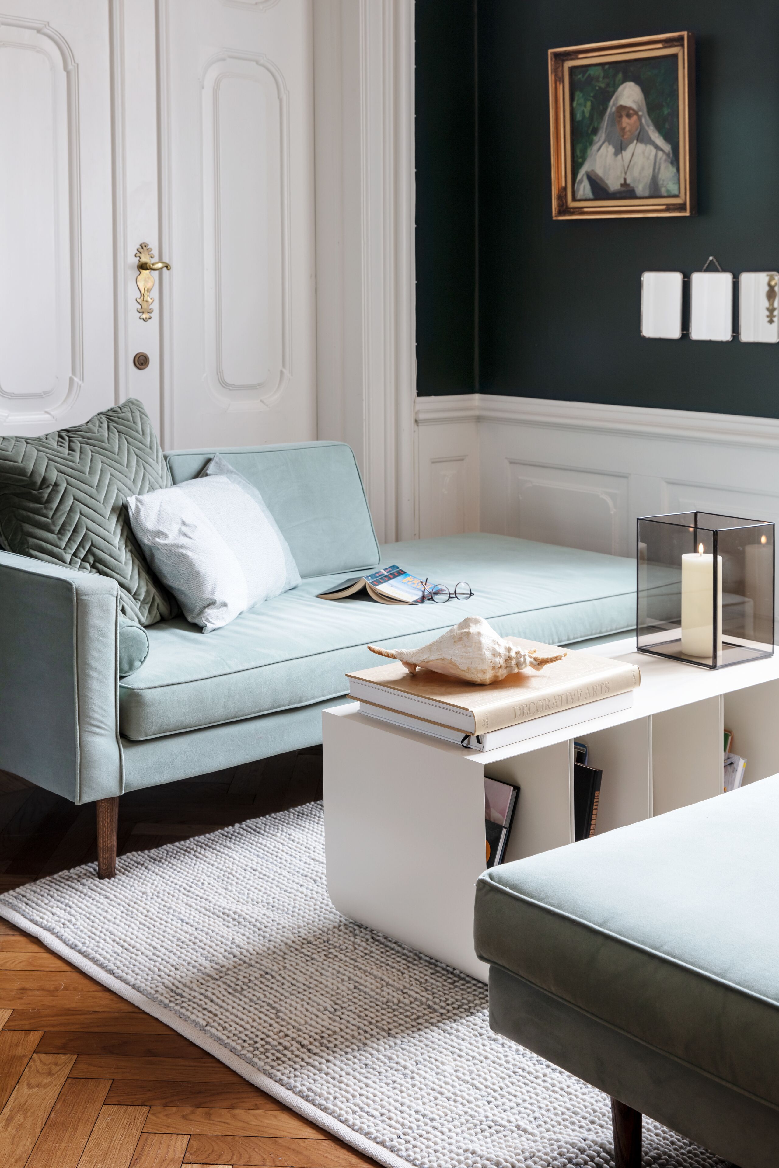 A room with a light blue sofa, a white coffee table, and a framed picture on the wall.