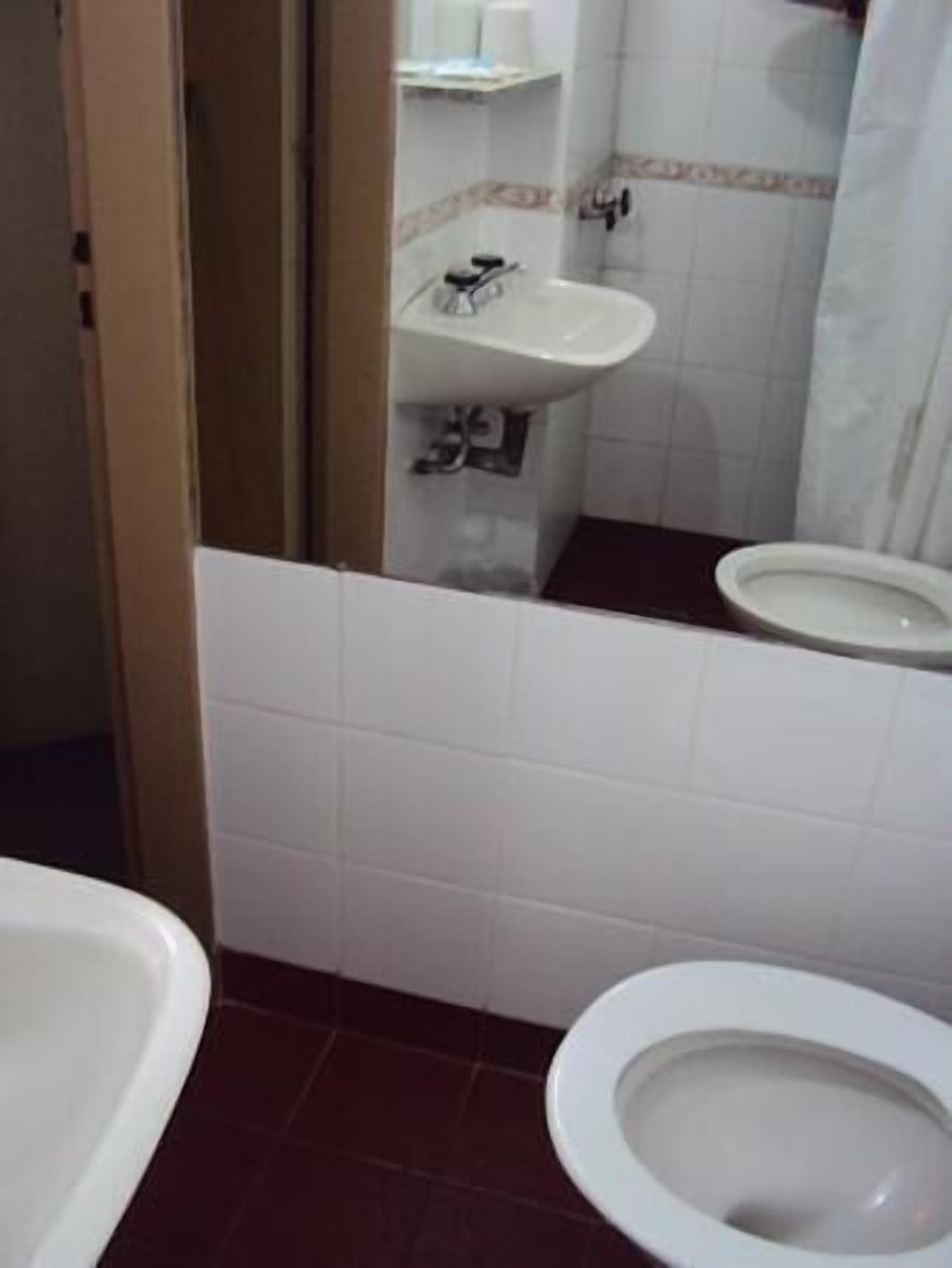 A bathroom with a toilet, a sink, and a mirror.