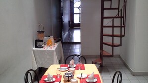 A dining area with a table set for four, a staircase, and a view of the interior. - Hotel del Prado (Buenos Aires)