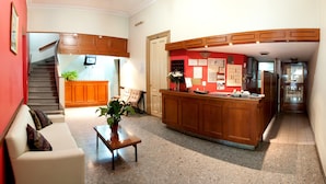 A spacious living area with a kitchen, a staircase, and a reception desk. - Hotel del Prado (Buenos Aires)